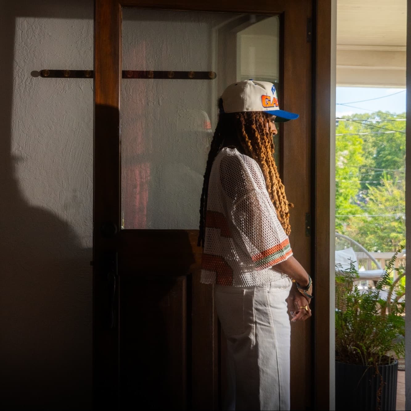 Jackie Hill Perry in a doorway, light from outside, her shadow on the wall