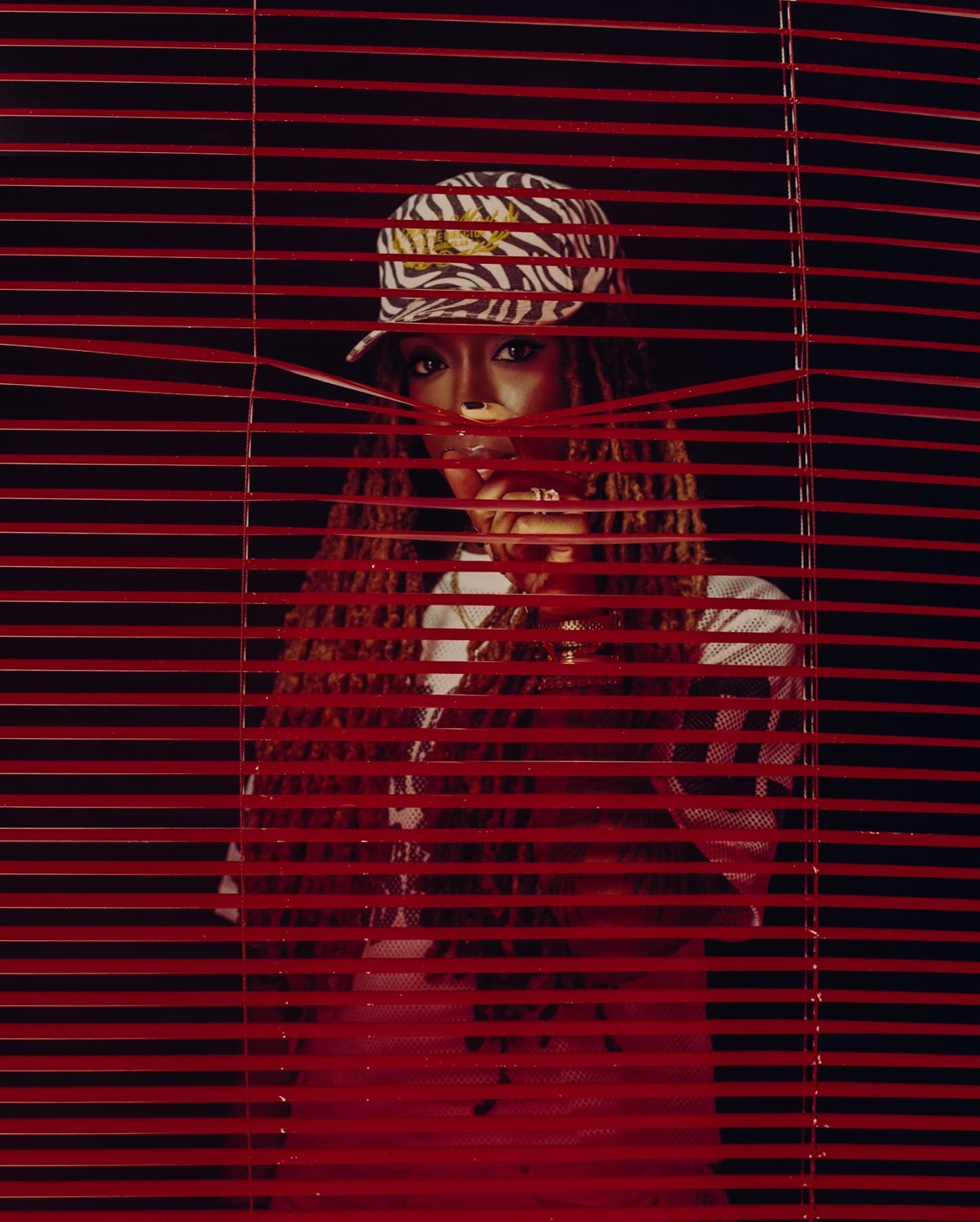 Jackie Hill Perry looking through red blinds